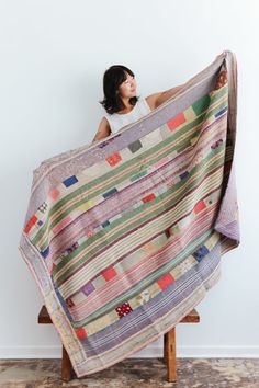 a woman is sitting on a chair holding a quilt