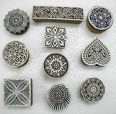 six different metal stamp designs on a white table top, each with an intricate design in the middle