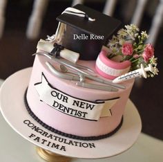 a pink cake decorated with graduation caps, flowers and other items on top of it