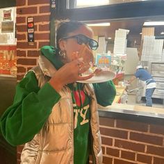 a woman eating food from a plate in front of a brick wall at a fast food restaurant