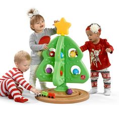 three children playing with a toy christmas tree