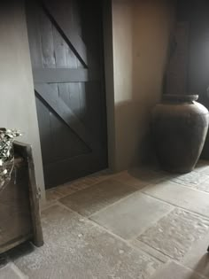 a large vase sitting on top of a floor next to a wooden door