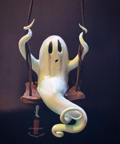 a fake ghost sitting on a swing with two hands hanging from it's sides