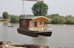 a houseboat floating on top of a river next to a dock with a crane