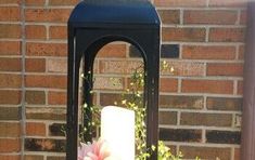 a black lantern with flowers in it sitting next to a brick wall