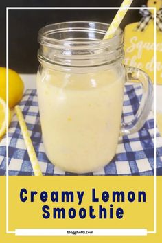 a mason jar filled with creamy lemon smoothie next to two lemons and a straw