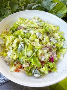 a white bowl filled with lettuce and other food items on top of a table