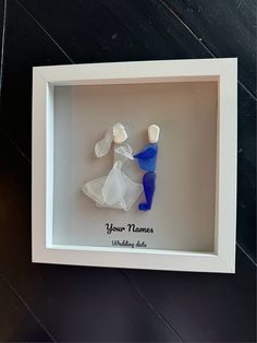 a white shadow frame with two blue and white glass figures in it that says your names