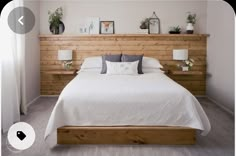 the bed is made with white linens and wooden headboard