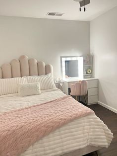 a bedroom with a bed, dresser and mirror in the corner that has a pink blanket on it