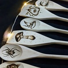 six wooden spoons with designs on them are lined up in a row against a black background