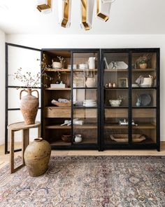 a room that has some glass doors and shelves in it with vases on the floor