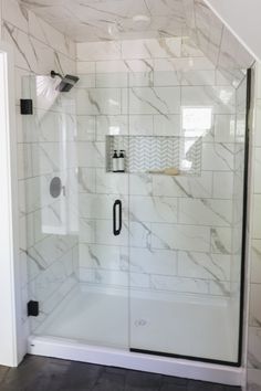 a walk in shower sitting next to a white tiled wall and floor covered in marble