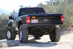 a black pickup truck driving down a dirt road