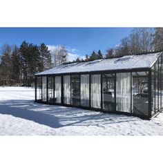 a small glass house sitting in the middle of a snow covered field with lots of trees