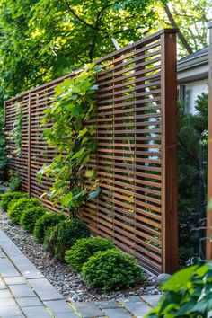 a wooden fence in the middle of a garden with lots of greenery on it