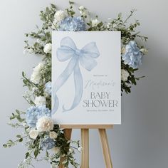 a baby shower sign with blue flowers and greenery