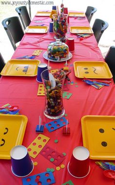 a table set up for a birthday party with plates and cups filled with candies