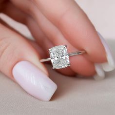 a woman's hand holding a ring with a diamond on the middle of it