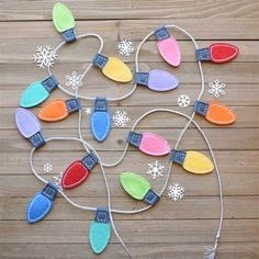 an assortment of felt christmas lights on a wooden table with snowflakes in the background