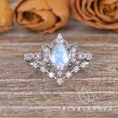 an opal and diamond ring with roses in the background