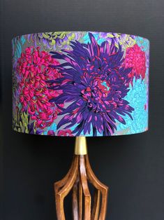 a purple flower lamp on a wooden table with a blue lampshade over it