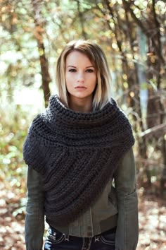 a woman standing in the woods wearing a knitted shawl