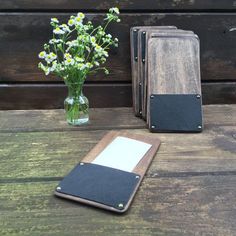 a wooden table topped with a vase filled with flowers next to an empty notepad