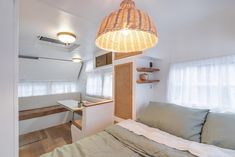 a bed sitting under a light next to a window in a room with wooden floors