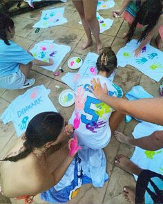 a group of people sitting on the ground with t - shirts covered in handprints