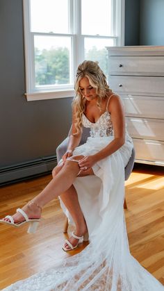 a woman sitting on top of a chair in a room with a window behind her