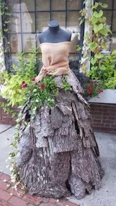 a dress made out of a tree stump with flowers growing on the top and bottom