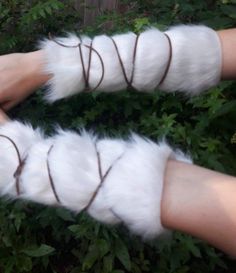 two hands with white and brown furry gloves on them, tied up to each other