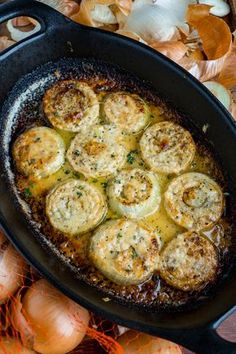 an iron skillet filled with food sitting on top of a table next to onions