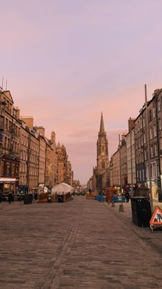 an empty city street with buildings on both sides and a clock tower in the distance