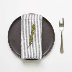 a plate with a fork, knife and napkin on it next to a striped napkin