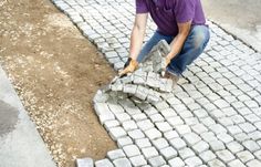 a man is laying bricks on the ground