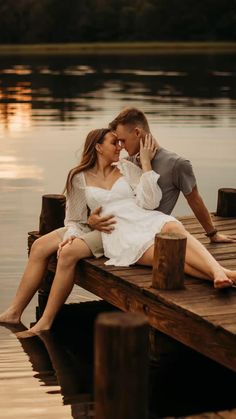 a man and woman sitting on a dock kissing