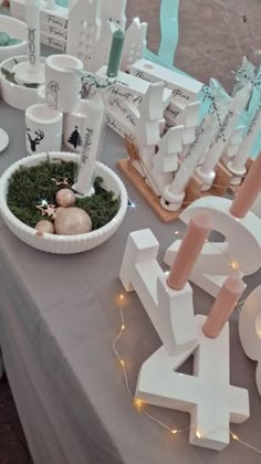 a table topped with candles and decorations on top of a gray table cloth covered table