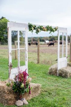 an old door is decorated with flowers and greenery in the middle of a field