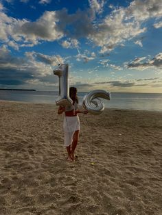 a woman on the beach holding an inflatable number one balloon