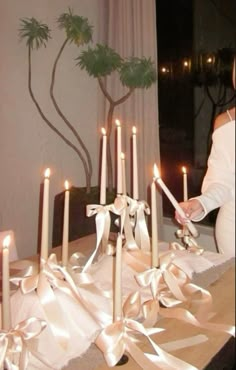 a woman standing in front of a table with many candles on it and ribbons around the table