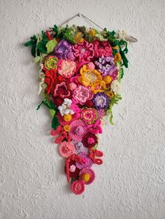 a wall hanging with crocheted flowers on it's side and a pair of scissors next to it