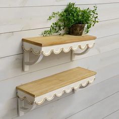 two wooden shelves with plants on them against a white painted wall, one shelf has a potted plant and the other is empty