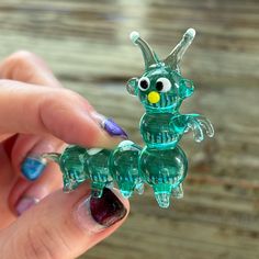 a hand holding a green glass figurine that looks like a bird with big eyes