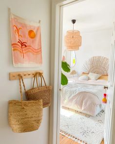 a room with a bed, rugs and baskets hanging on the wall next to it