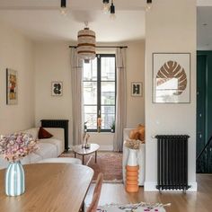 a living room filled with furniture and a wooden table in front of a window next to a radiator