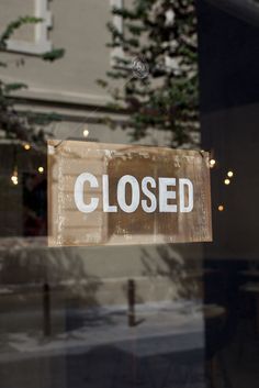 a closed sign hanging from the side of a glass door in front of a building