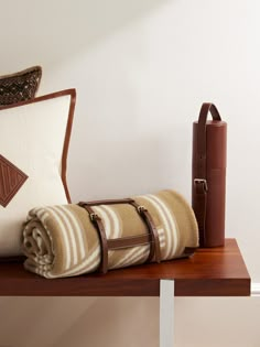 a couple of pillows sitting on top of a wooden table next to a brown suitcase