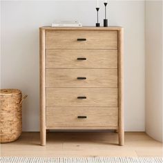 a wooden chest of drawers next to a basket